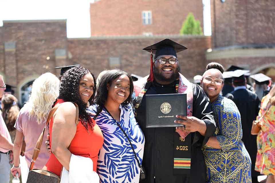 A graduates poses for a photo with family after Commencement